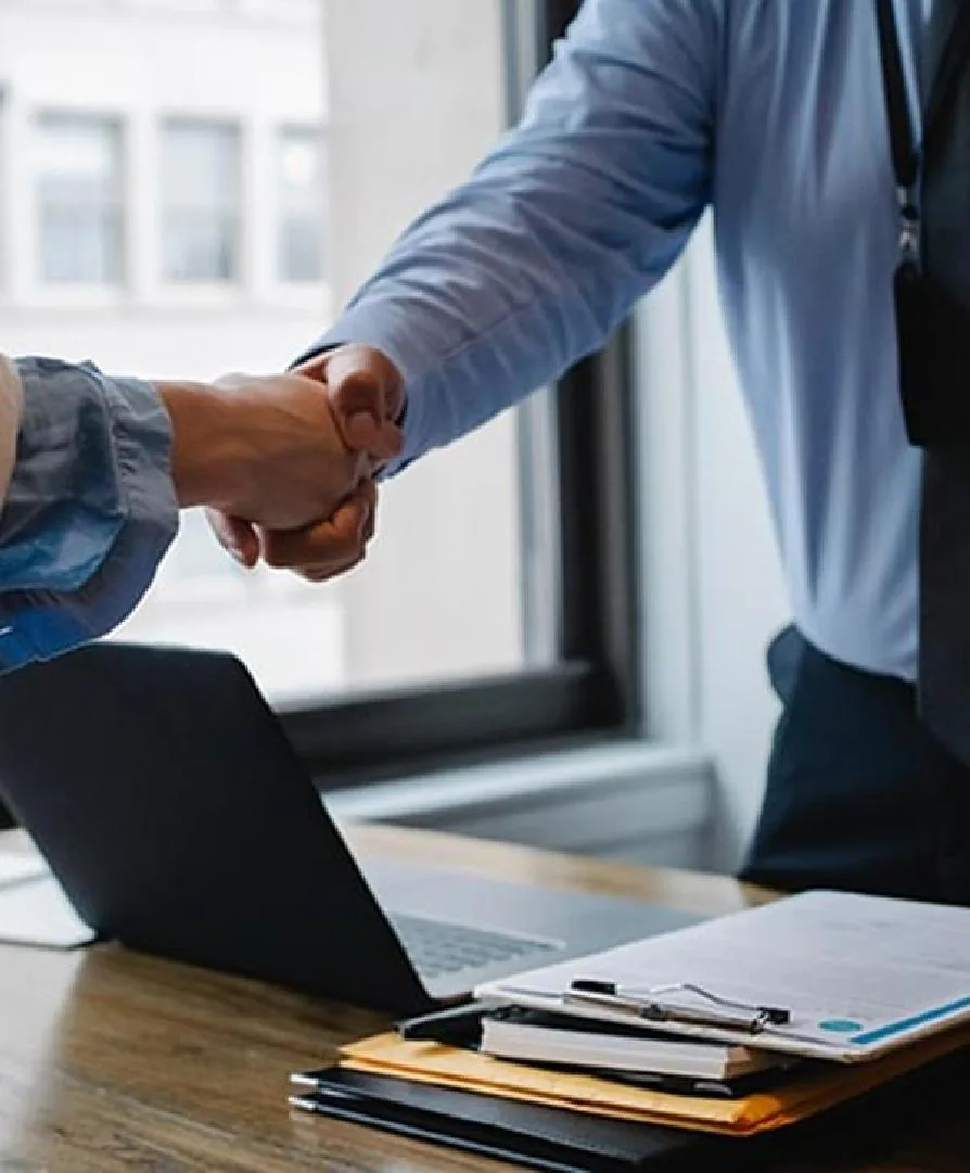 Two professionals shaking hands over a contract